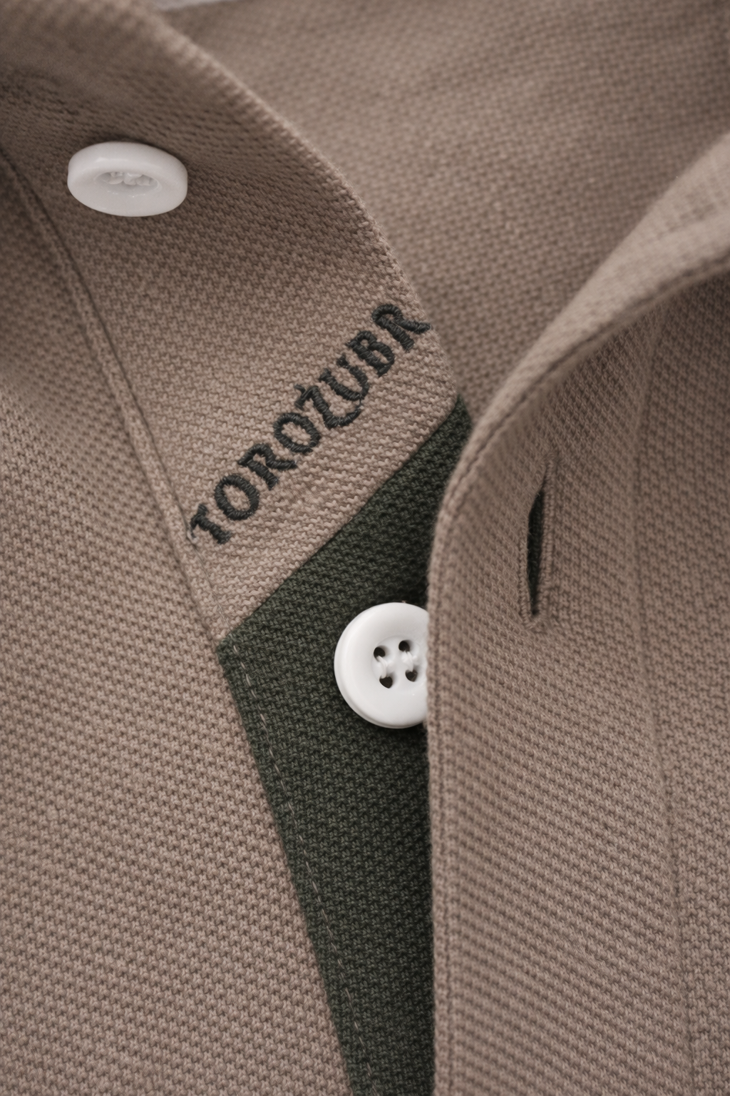 Close-up of polo neck placket with 'TOROZUBR' branding and white buttons. #color_umber