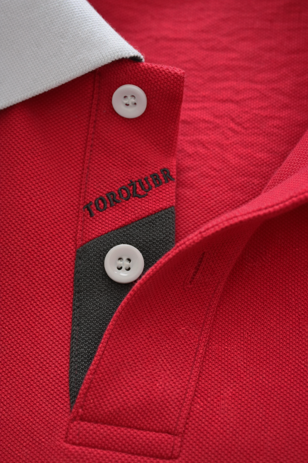 Close-up of a red polo shirt with a white button and 